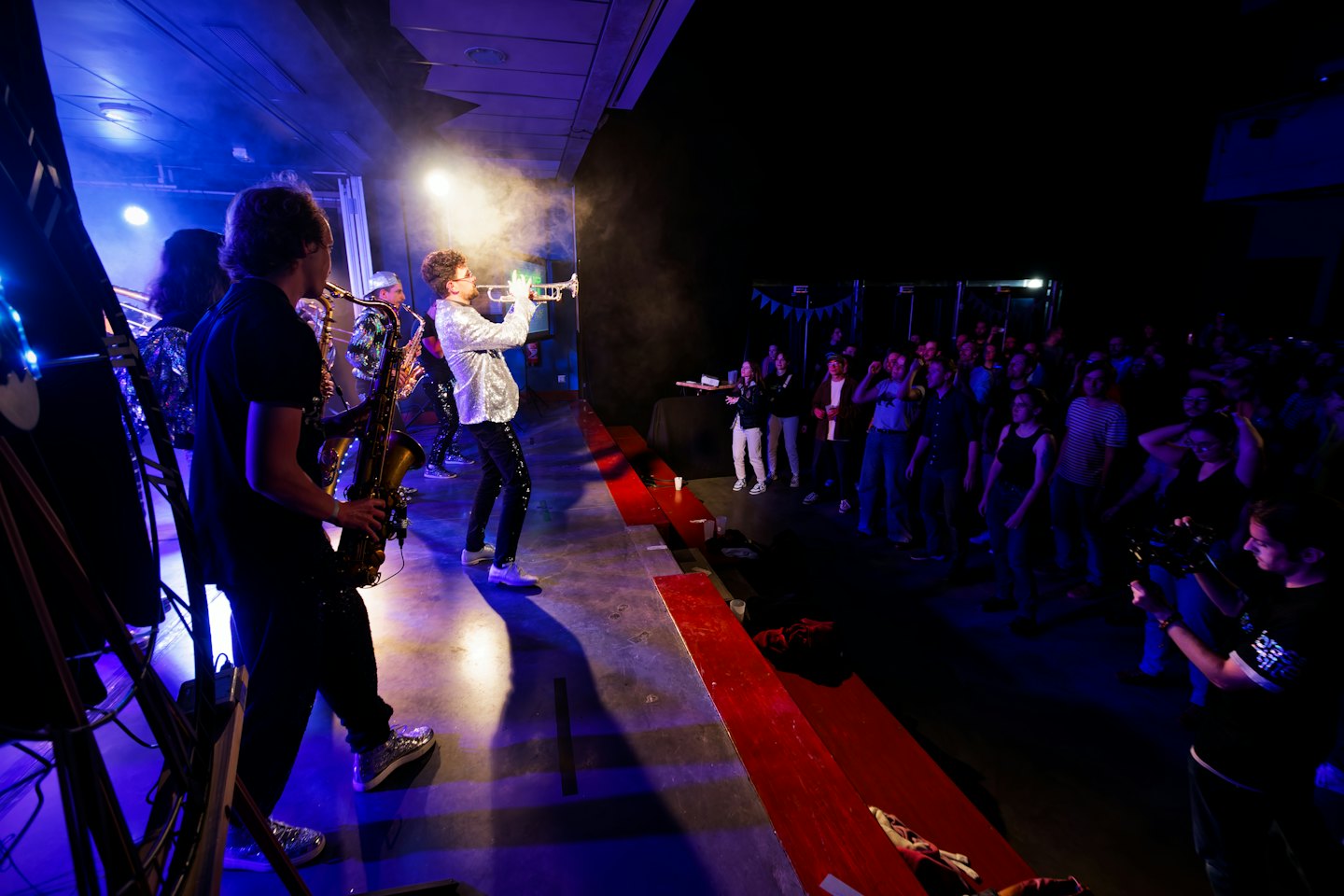Muzycy grają na instrumentach dętych na scenie przed publicznością.